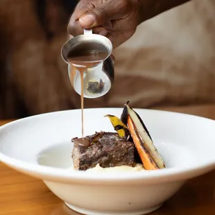 Beef short ribs, braised in a red wine demi sauce, served with whipped potatoes and chef&apos;s daily vegetables