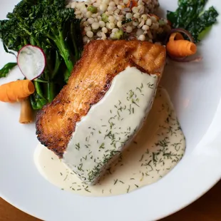 Seared Salmon, served with a Mediterranean couscous, chef&apos;s daily vegetable and a dill beurre Blanc