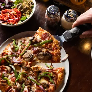 a person cutting a slice of pizza