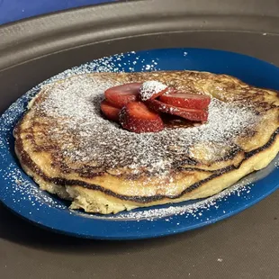 a plate of pancakes with strawberries and powdered sugar