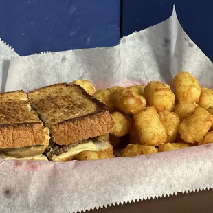 a sandwich and tater tots in a basket