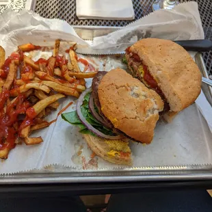 Burger with gluten free bun, and one bite taken out.