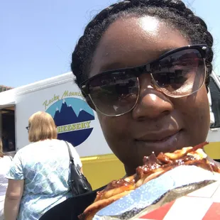 a woman in sunglasses holding a large piece of pizza