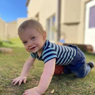 Child crawling on grass.