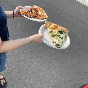 a woman holding two plates of pizza
