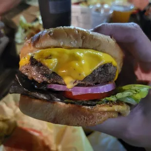 a hand holding a cheeseburger