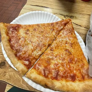 two slices of cheese pizza on a paper plate