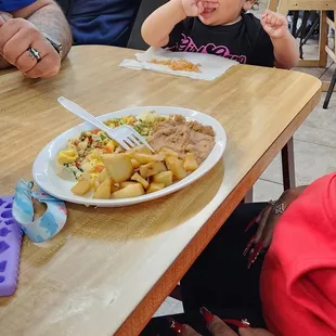 a young child sitting in front of a plate of food