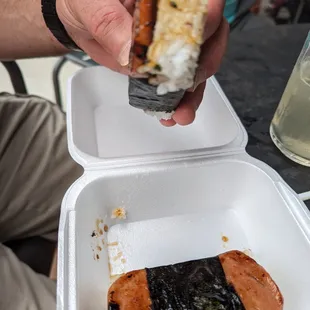 a person holding a hot dog in a styrofoam container