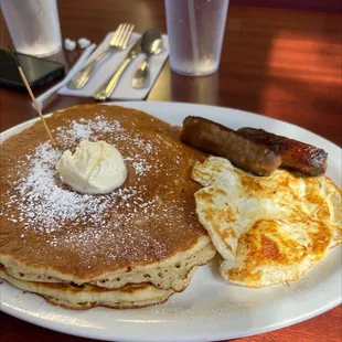 a plate of pancakes, sausages, and eggs