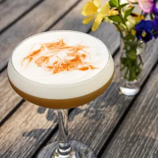 a cocktail in a coupe glass on a wooden table