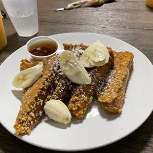 a plate of french toast with bananas and syrup