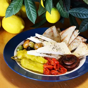 a plate of pita bread, olives, pickles, and tomatoes