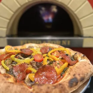 a pizza in front of a brick oven