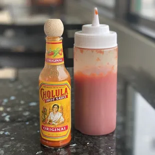 a bottle of hot sauce next to a bottle of sauce