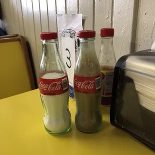 two coke bottles on a yellow table