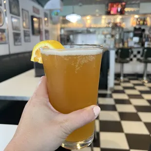 a hand holding a glass of orange juice
