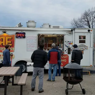 a group of people standing around a food truck