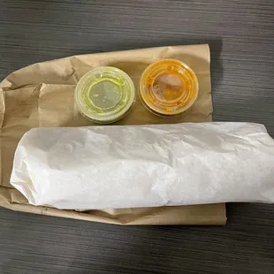 Huge wrapped up burrito with green and red salsa