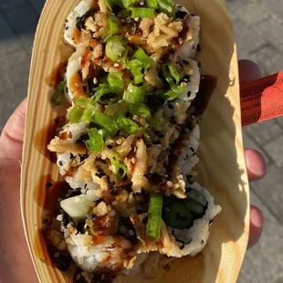 a hand holding a roll of sushi