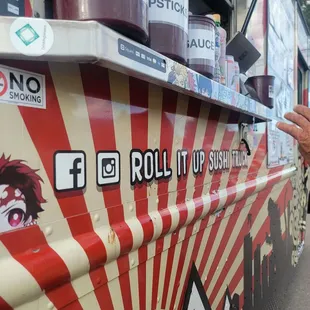 a man standing in front of a roll it up sushi truck
