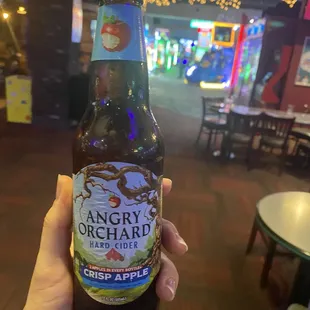 a hand holding a bottle of angry orchard