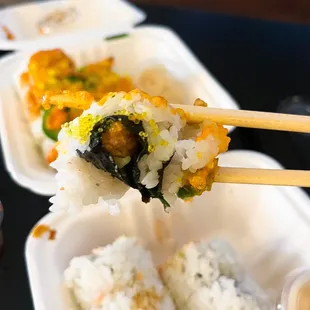 a pair of chopsticks holding a piece of sushi