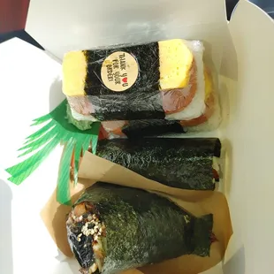 Eel onigiri, eel hand roll in the middle and two spam musubi with egg