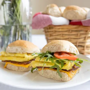 two sandwiches on a plate with a vase of flowers in the background