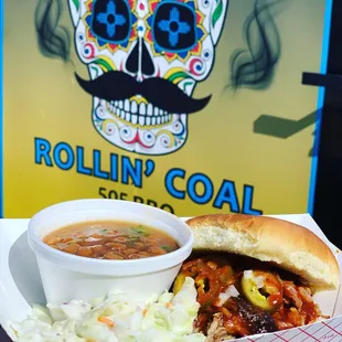 a hand holding a sandwich and a bowl of chili