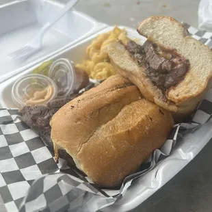 A ribeye steak sandwich w grilled onions and a side of mac n cheese. Made to perfection