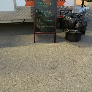 a chalkboard sign and trash bags