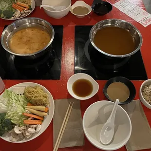 a red table with bowls of food and chopsticks