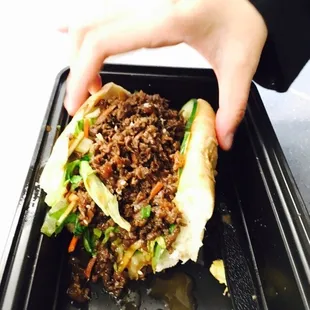 a person holding a sandwich in a black container