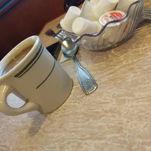 a cup of coffee with marshmallows in the background