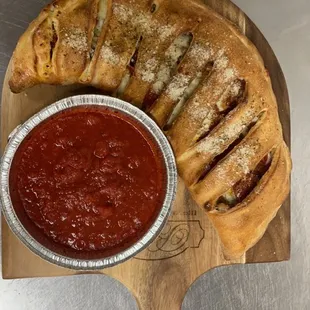 a pizza and a bowl of tomato sauce