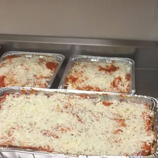 four pans of lasagna ready to be cooked