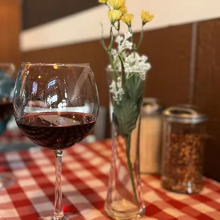 a glass of wine and a vase of flowers