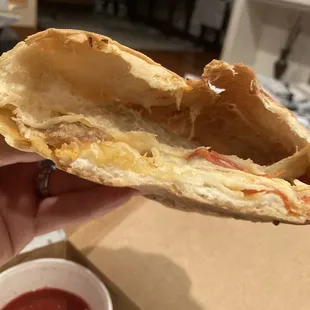 a hand holding a half eaten sandwich