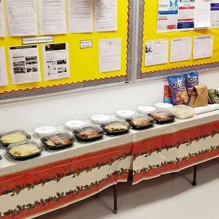 a long table of food in front of a bulletin board