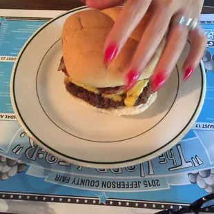 a woman's hand holding a hamburger on a plate
