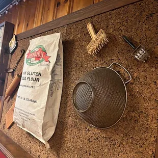 a pizza pan, a frying pan, a bag of flour, a spatula, and a