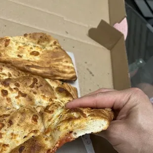 a hand holding a piece of pizza