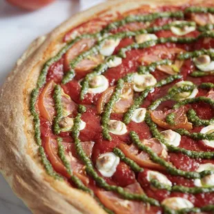 Margherita Pizza - Tomatoes, Fresh Mozzarella, Original Pizza Sauce topped with a swirl of Basil Pesto