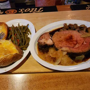 Queen cut prime rib with green beans, baked potato, and garlic bread