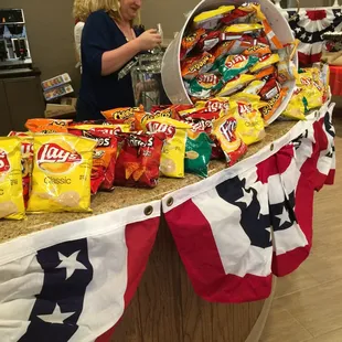 a woman standing behind a counter full of chips