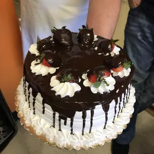 a man holding a chocolate covered cake