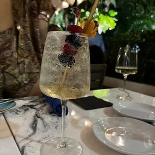 a glass of wine with a fruit garnish