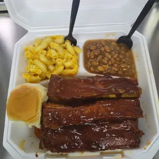 ribs, beans, macaroni and cheese in a styrofoam container