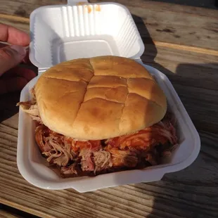 a pulled pork sandwich in a styrofoam container